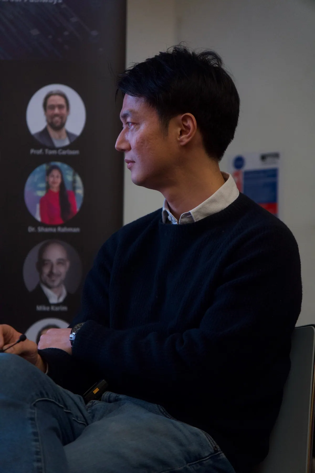 A speaker seated beside the symposium speaker banner