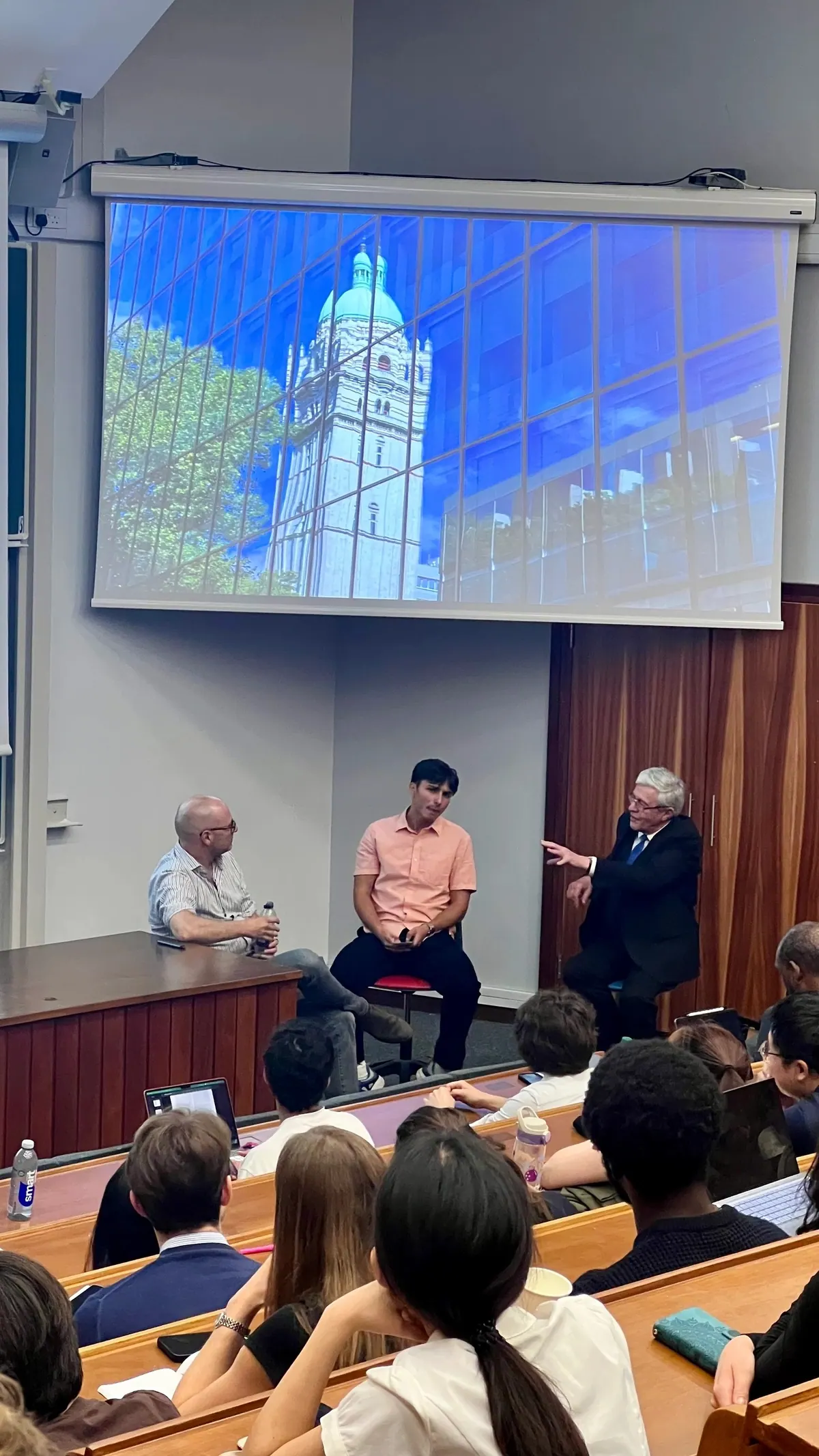 A panel discussion in front of a projected image of a building