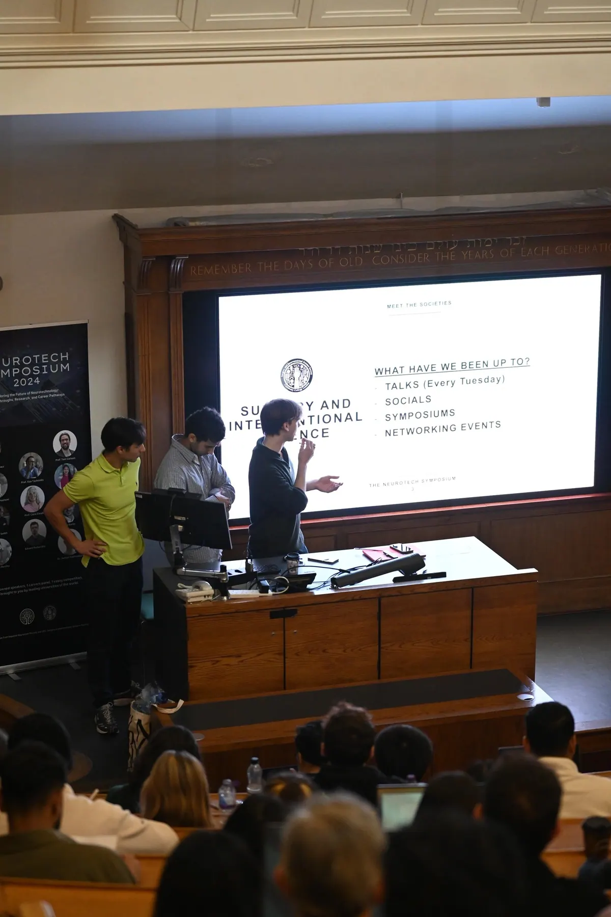 Presenters on stage in front of a projected slide